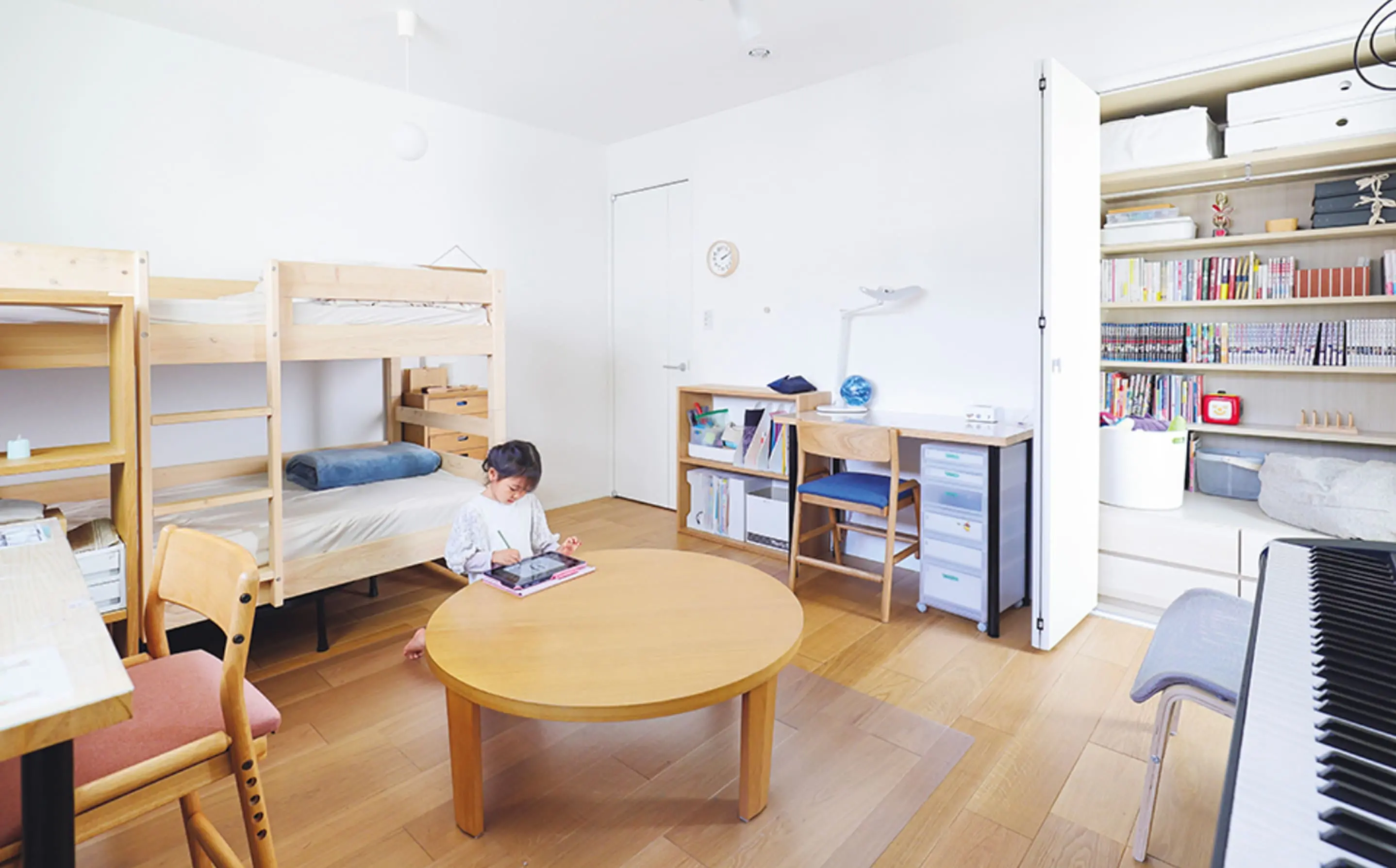 二段ベッドと勉強机、たくさんの本が収納された本棚がある子ども部屋で、女の子が床でお絵描き中