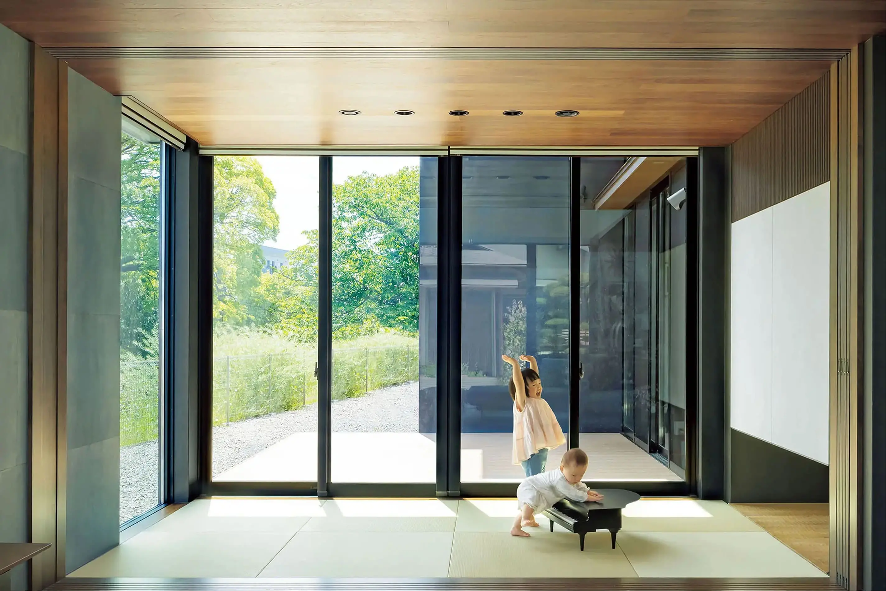 大きな窓から光が差し込む和室で、幼い姉妹が遊んでいる微笑ましいひととき