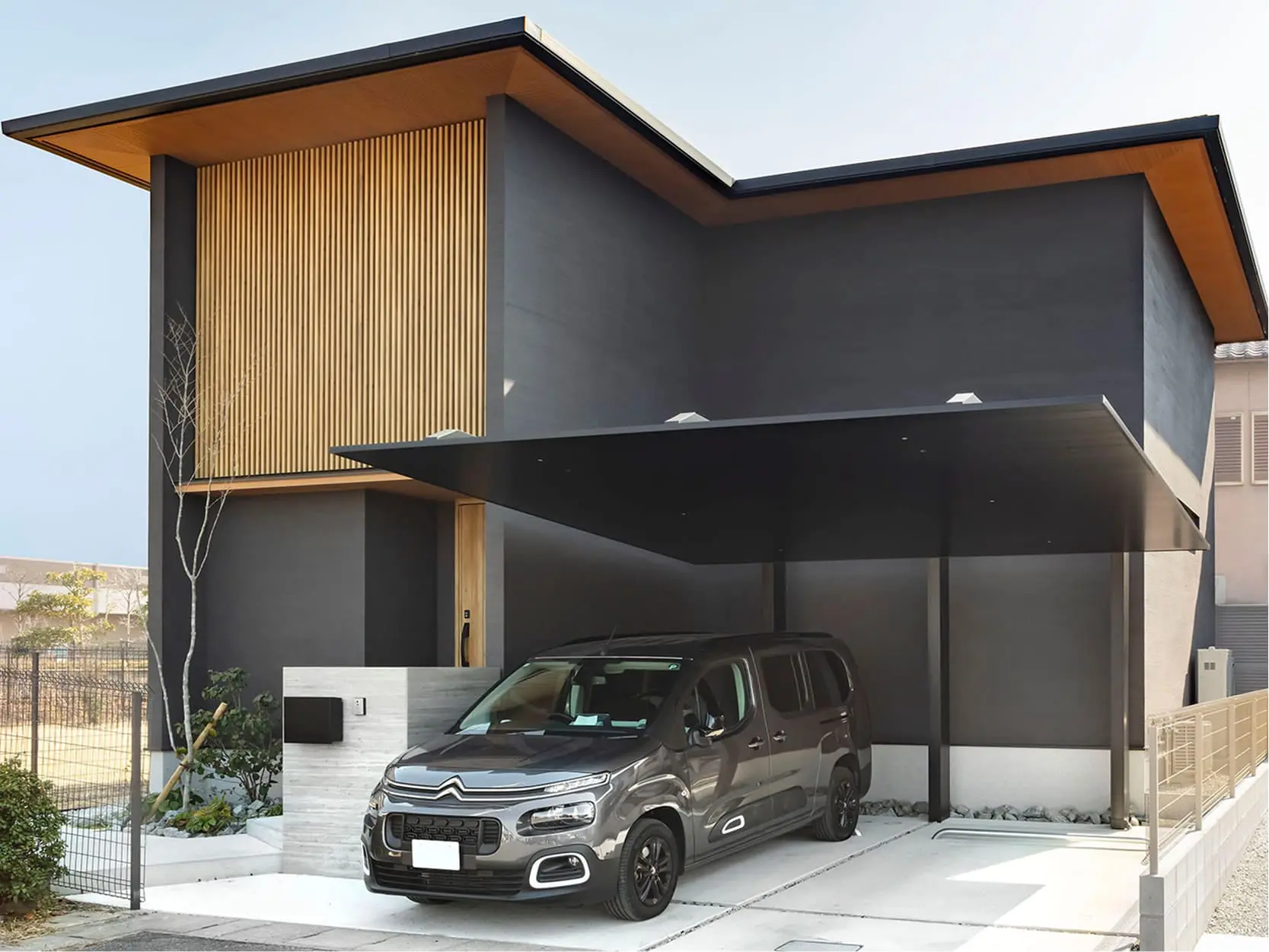 アイアン階段と大きな観葉植物が印象的な玄関ホールで、ガラスの間仕切りが空間を広く見せている